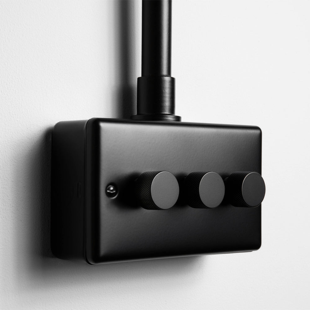 Matt Black 3 Gang 2 Way LED Dimmer Switch With Back Box And Conduit On A Light Grey Background