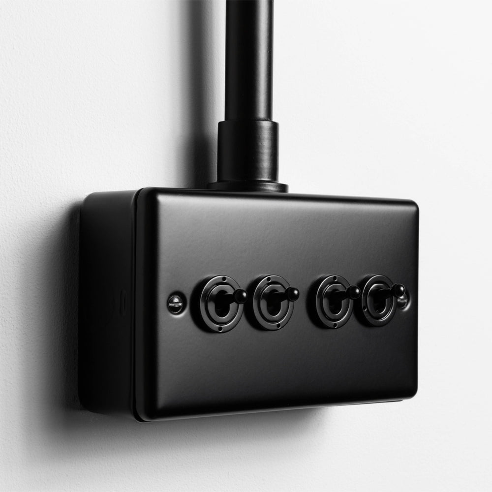 Matt Black 4 Gang 2 Way Toggle Switch  With Back Box And Conduit On Light Grey Wall