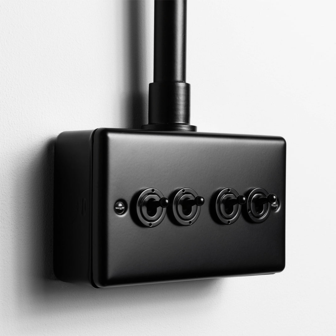 Matt Black 4 Gang 2 Way Toggle Switch  With Back Box And Conduit On Light Grey Wall
