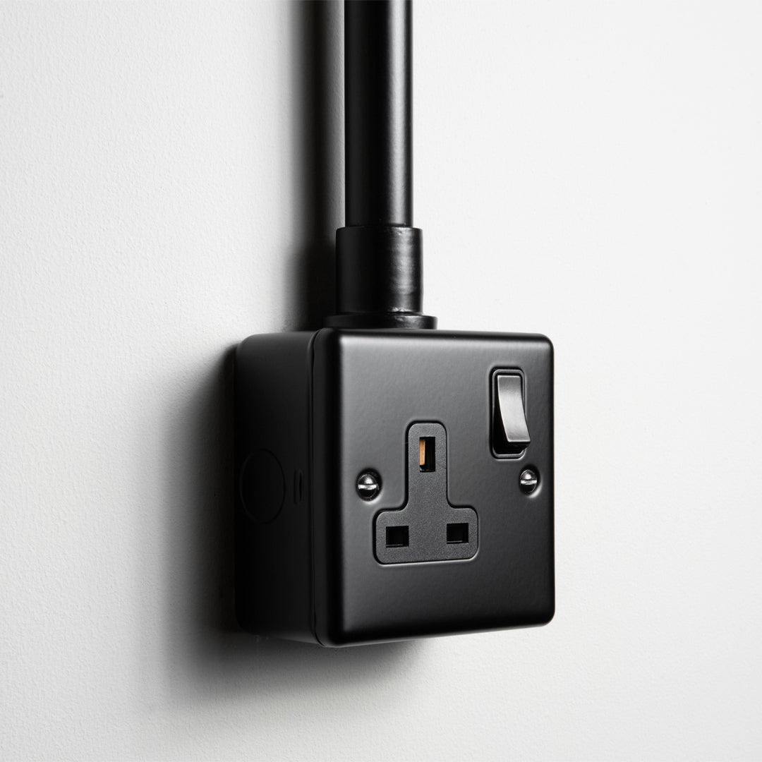 Matt Black Single Socket With Back Box And Conduit On A Light Grey Background