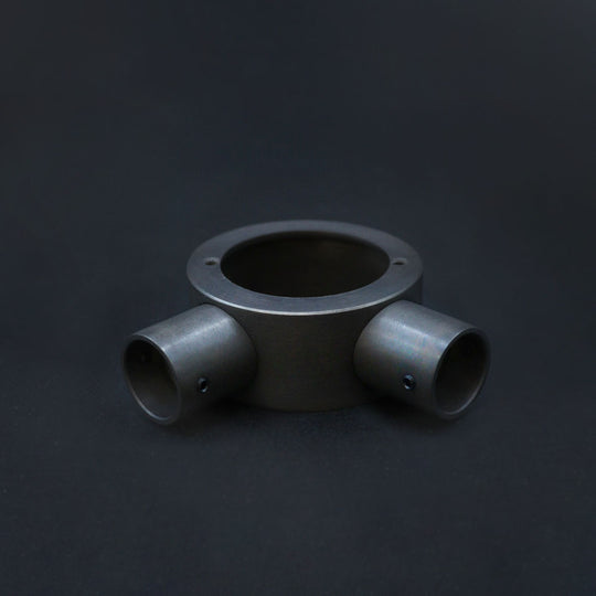 A dark bronze angle box with conduit, machined from solid brass on a ark background