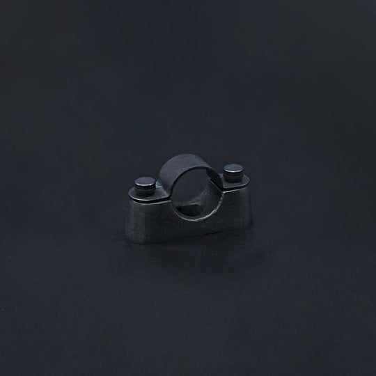 A dark bronze conduit saddle with a solid brass base and top strap, featuring matching knurled head M4 fixing screws, against a dark background.
