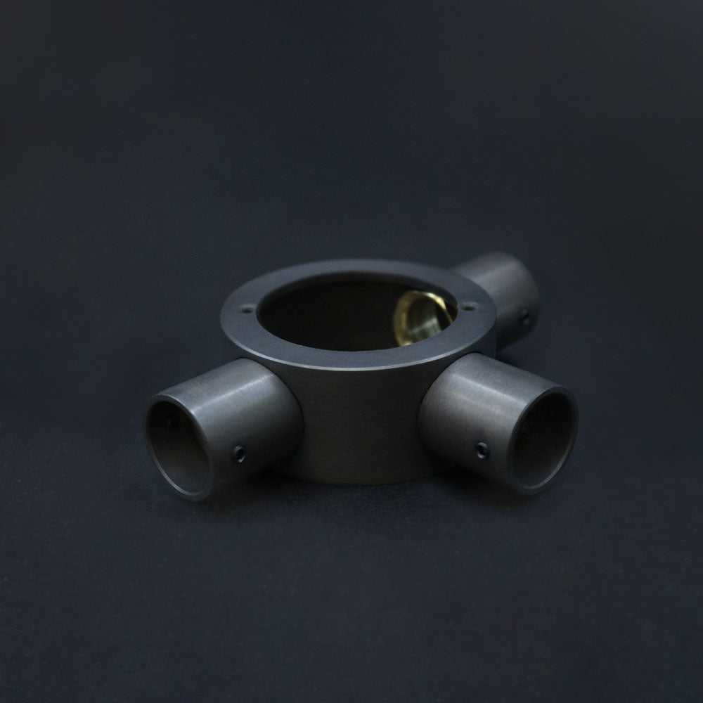 A dark bronze 20mm conduit tee box with three outlets, placed against a dark background.