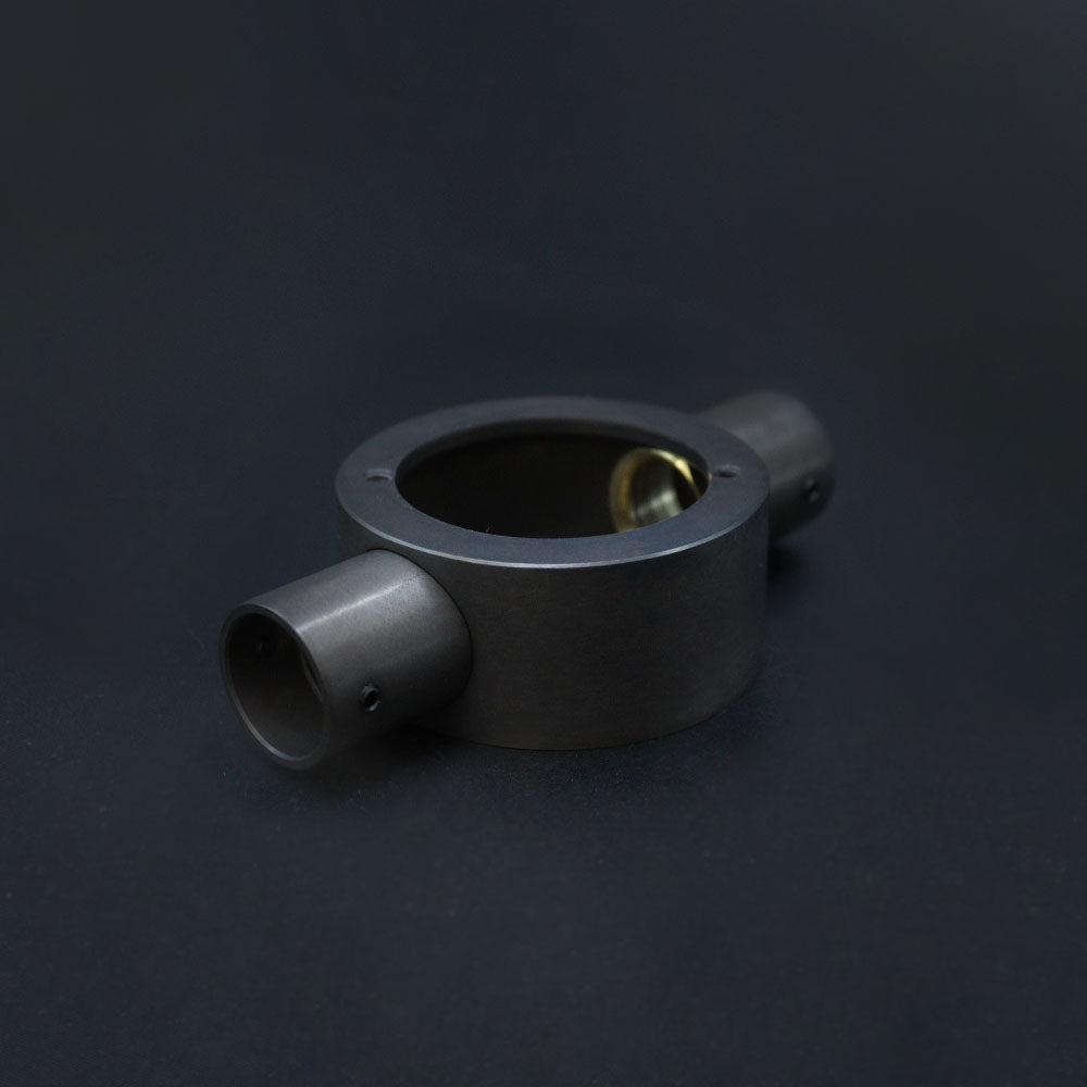 A dark bronze metal conduit through box placed against a dark background.