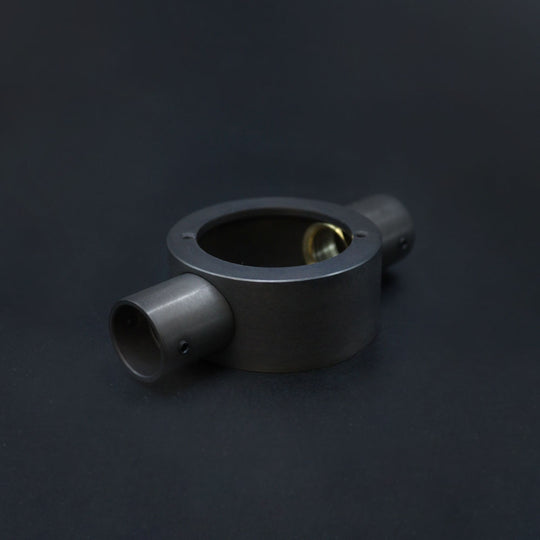 A dark bronze metal conduit through box placed against a dark background.